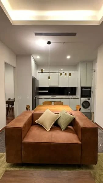 Living features: brown leather sofa, two decorative cushions, pendant lighting with multiple bulbs, wooden dining table, four wooden dining chairs, open kitchen layout, white cabinetry, black countertop, built-in oven, stainless-steel fridge, washer-dryer combo, wood flooring, recessed ceiling lights, neutral wall color; style: modern.