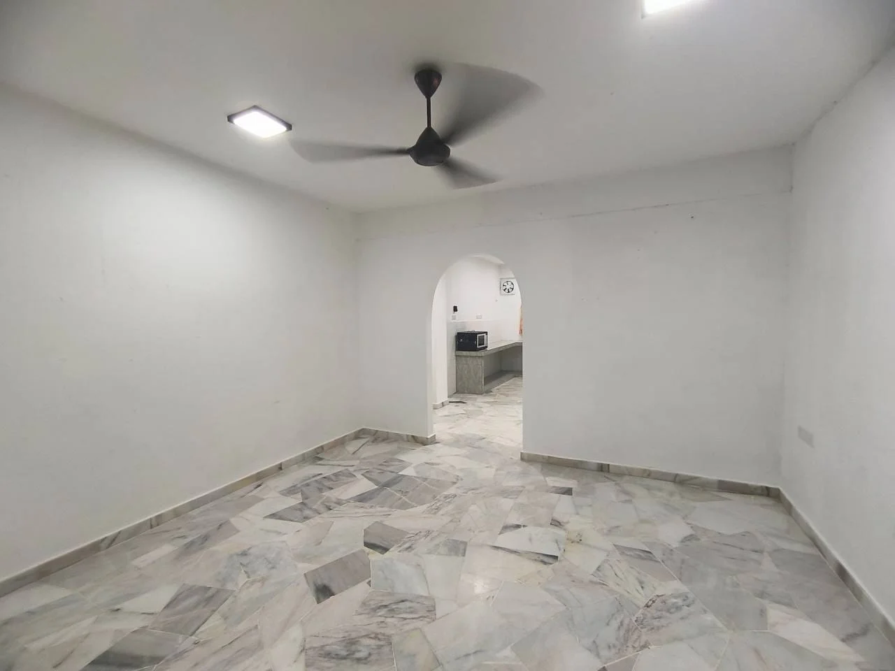 Room features: white painted walls, marble flooring, ceiling fan, recessed LED downlights, arched doorway, open layout, kitchen visible in background; style: modern.