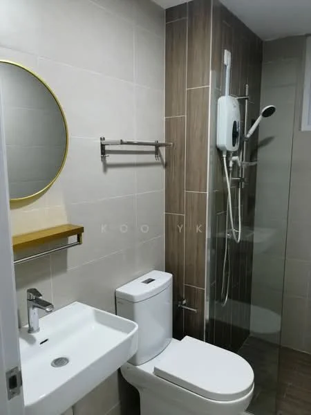 Bathroom features: white ceramic sink, chrome basin mixer faucet, round mirror with gold frame, white one-piece toilet, glass shower enclosure, handheld showerhead, wall-mounted shower unit, wooden shelf, grey tiled walls, brown tiled flooring; style: modern.