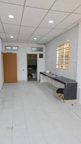 Room features: white painted walls, grey tiled flooring, drop ceiling with recessed lights, single-bowl stainless-steel sink, black countertop, wooden door, window with wooden grille, toilet visible in the background; style: modern.
