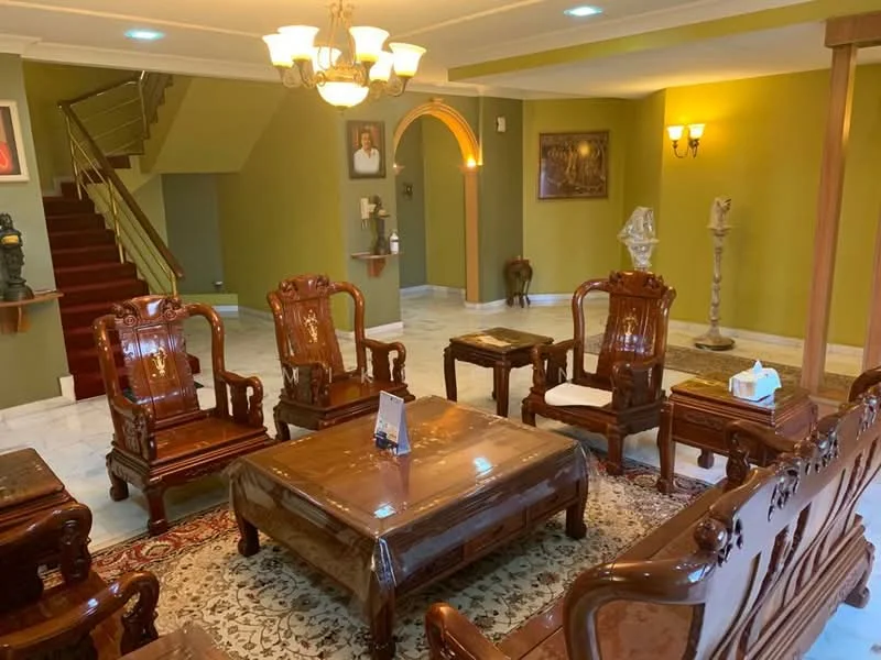 Living features: marble flooring, green painted walls, chandelier, 5-blade ceiling fan with light, wooden coffee table, wooden armchairs with intricate carvings, decorative area rug, wall sconces, staircase in background, sculptures and decorative items, framed artwork on walls; style: traditional.