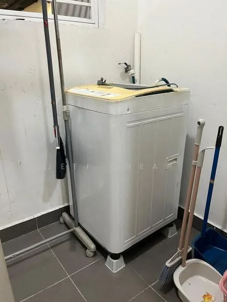 Laundry features: top-load washing machine in white, grey tiled flooring, white walls, utility sink, cleaning supplies, mop and broom, drainage pipe, window for natural light.