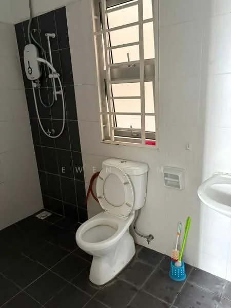 Bathroom features: white toilet, shower with wall-mounted water heater, grey tiled walls, black tiled accent wall, black floor tiles, window with metal grille, sink with wall-mounted faucet, toilet paper holder, cleaning brush, shower curtain rod.