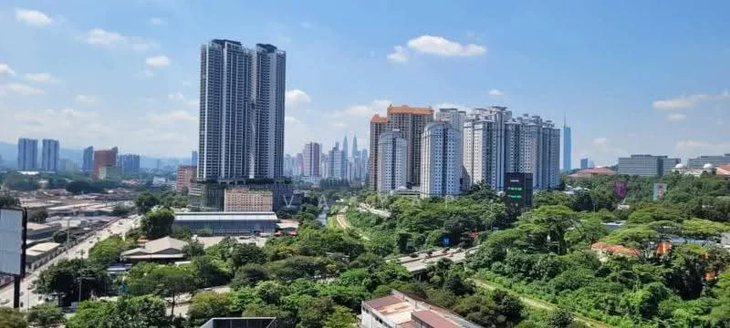 Exterior type: high-rise condominium; features: glass curtain wall, surrounded by mature greenery, urban skyline view, multiple high-rise buildings, roadway visible in foreground, mixed-use development, varied architectural styles, tropical landscaping; style: modern.