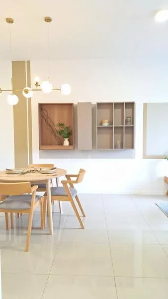 Dining features: round wooden dining table, 4 wooden dining chairs, white ceramic plates on the table, pendant light fixture with multiple bulbs, light wood cabinetry, open shelving unit, decorative plant on shelf, white tiled flooring, neutral painted walls, wall-mounted mirror; style: modern.