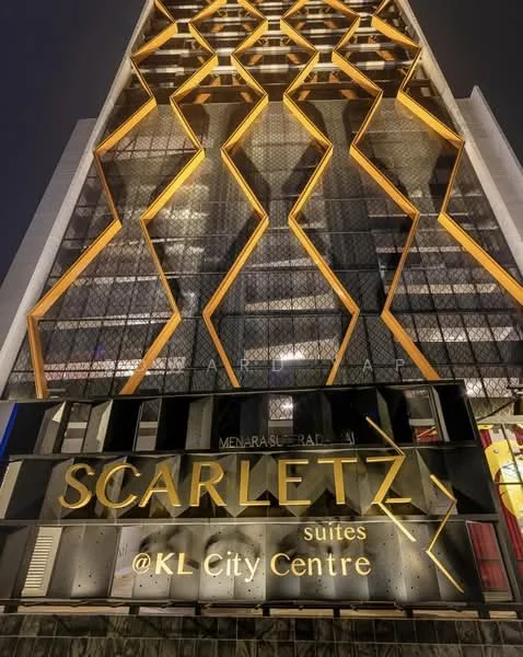 Exterior type: high-rise condominium; features: glass curtain wall, exposed concrete facade, geometric pattern on facade, illuminated signage, gold accents, multiple balconies, modern architectural design; style: modern.