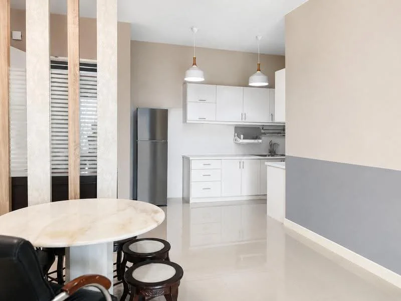 Kitchen features: white cabinetry, stainless-steel fridge, built-in sink, chrome faucet, white countertop, ceramic tile backsplash, pendant lighting, marble dining table, 4 wooden dining chairs, polished tile flooring, grey accent wall, window with blinds; style: modern.