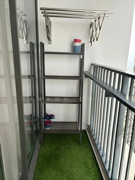 Balcony features: metal railing, artificial grass flooring, open shelving unit, clothes drying rack, colorful cup, shoes on floor; view: city.