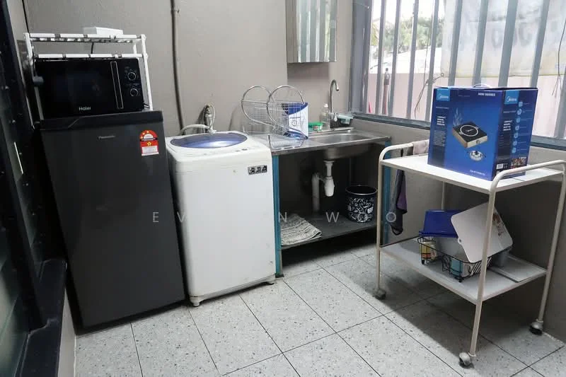 Laundry features: white washing machine, stainless-steel sink, black fridge, microwave oven, metal drying rack, white rolling cart, grey tiled flooring, window with metal bars.