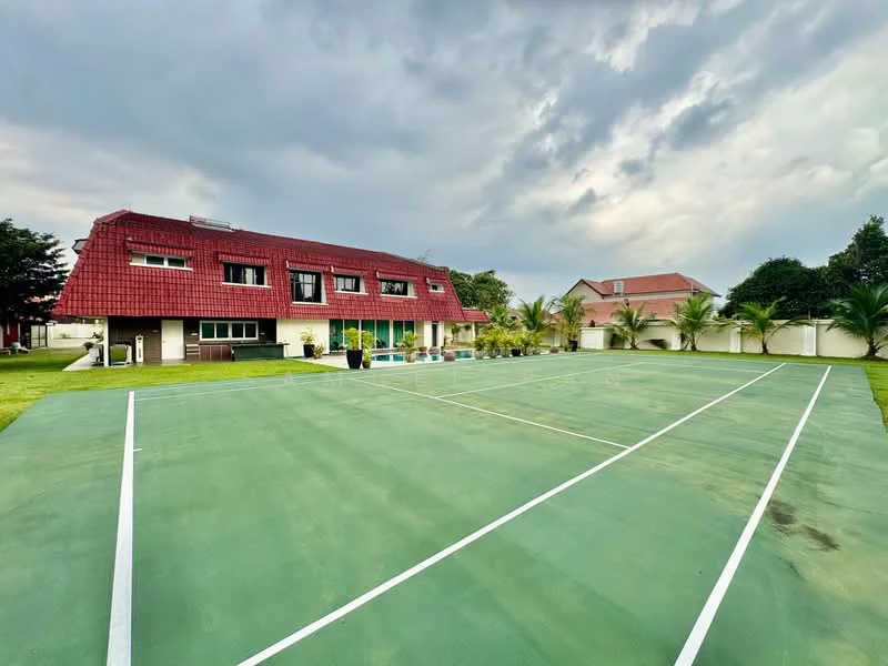 Exterior type: detached bungalow; features: red tiled roof, two-storey building, green tennis court, manicured lawn, surrounded by palm trees, outdoor swimming pool, patio area, landscaped garden, multiple windows, outdoor seating area; style: modern.