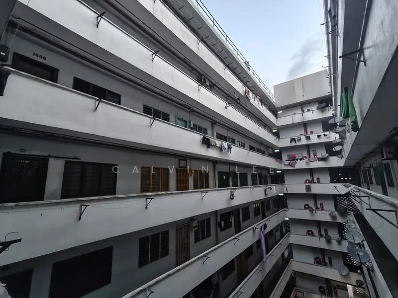 Exterior type: low-rise apartment block; features: multiple storeys, balconies with railings, exposed concrete facade, air conditioning units visible on walls, laundry hanging on balconies, windows with metal grilles, fire escape stairs, corridors connecting units; style: modern.