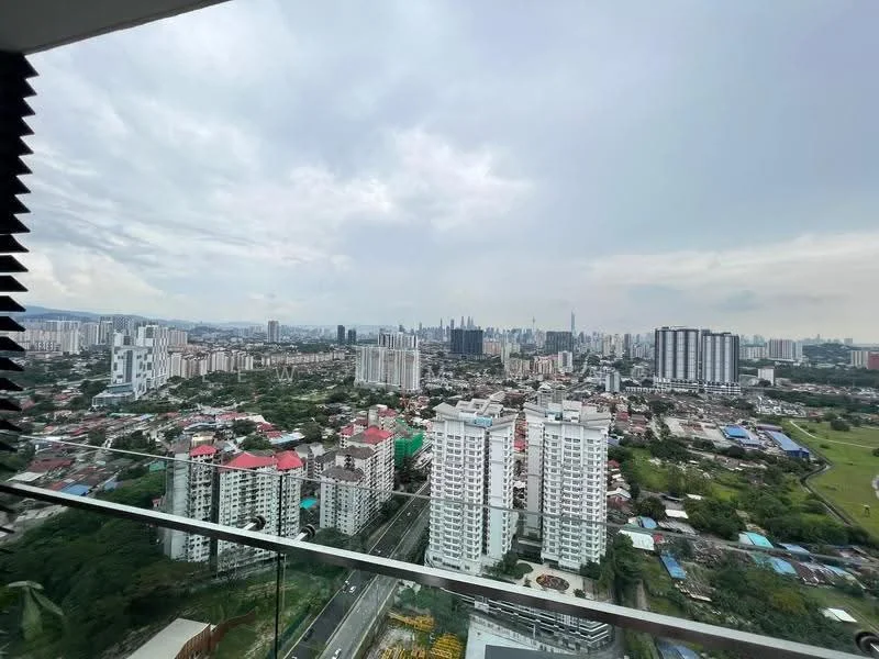 Exterior type: high-rise condominium; features: city skyline view, glass balcony railing, surrounding urban landscape, green spaces visible, multiple high-rise buildings, mixed architectural styles, distant landmarks visible, cloudy sky; style: modern.