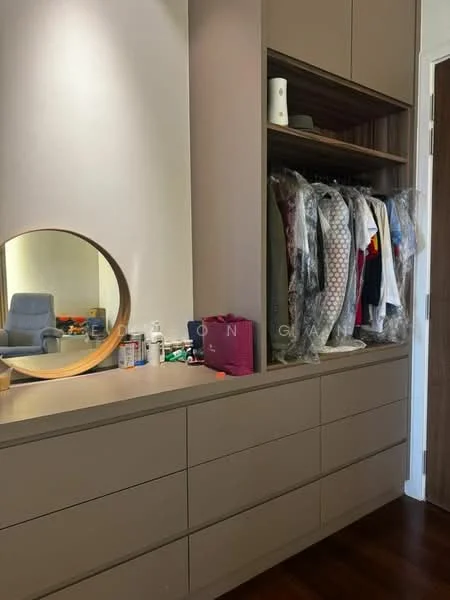 Bedroom features: built-in wardrobe with sliding doors, round mirror, wooden dresser with drawers, clothes on hangers, various personal items on dresser, wooden flooring, neutral wall color, soft lighting; style: modern.