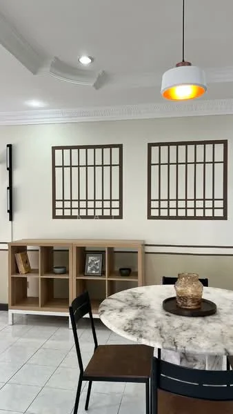 Dining features: round marble dining table, black dining chairs, wooden shelving unit, decorative vase on table, framed artwork on walls, white painted walls, crown moulding, recessed downlights, pendant light with orange accent; style: modern.
