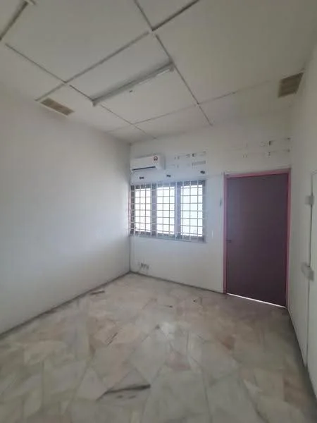 Room features: white painted walls, marble tile flooring, 2 windows with grilles, 1 wall-mounted split AC, single door with red frame, ceiling with tiles, light fixtures, corner location.