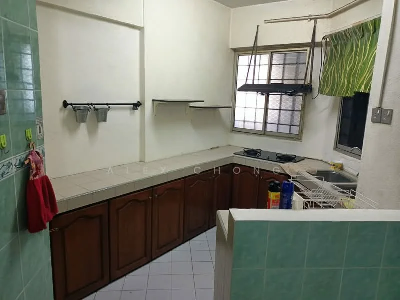 Kitchen features: green tiled backsplash, light green wall tiles, white painted walls, brown wooden cabinetry, laminate countertop, double-burner gas hob, stainless-steel sink, window with green curtains, open shelving, dish rack, hanging rack for utensils.