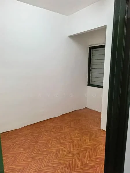 Room features: white painted walls, herringbone patterned wood flooring, single window with metal grille, green door frame.