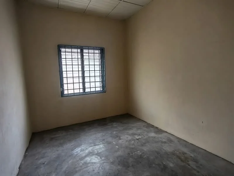 Room features: plain beige painted walls, concrete flooring, single window with metal grille, no visible ceiling features, no visible lighting fixtures; style: minimalist.