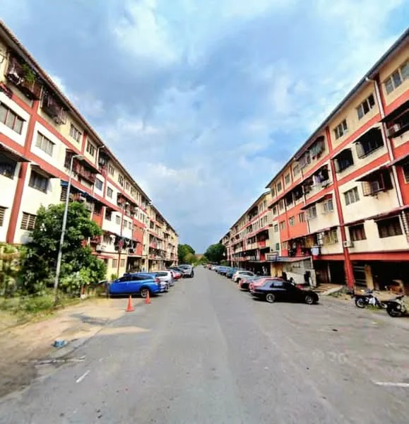 Exterior type: low-rise apartment block; features: two-storey building, red and cream painted facade, balconies with railings, parking spaces visible, surrounded by greenery, asphalt road, street lighting, multiple vehicles parked, sidewalks, windows with grilles; style: traditional.
