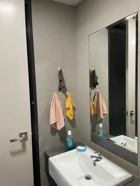 Bathroom features: grey tiled walls, white ceramic sink, chrome faucet, large mirror, dark cabinetry, hand towels hanging on hooks, soap dispenser, blue bottle, white wall, door with handle; style: modern.