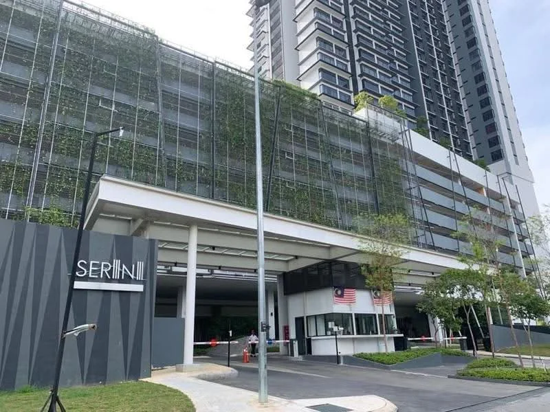 Exterior type: high-rise condominium; features: green wall with plants, covered entrance, security guard house, Malaysia flag, parking area, landscaped garden, modern facade, glass curtain wall, multiple storeys, driveway with interlocking pavers; style: modern.