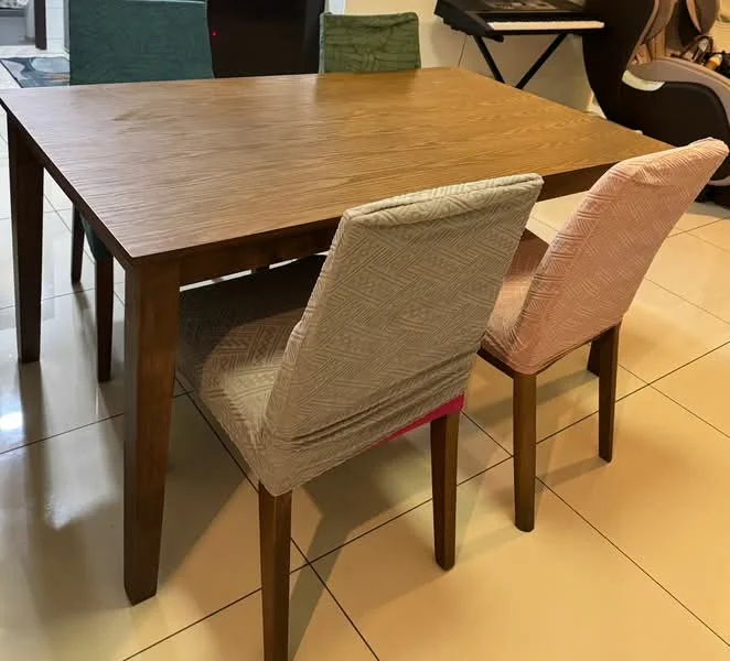 Dining features: wooden dining table, 4 upholstered dining chairs, grey chair with geometric pattern, pink chair with geometric pattern, cream chair with geometric pattern, glossy tiled flooring, neutral wall color, decorative items in background; style: modern.