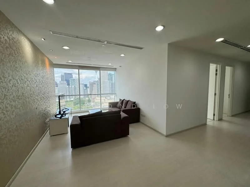 Living features: floor-to-ceiling windows, city view, cream painted walls, light-colored flooring, sofa in dark brown, TV console, wall-mounted TV, recessed downlights, decorative wall with pattern; style: modern; view: city. Room features: white painted walls, light-colored flooring, two doors leading to other rooms.