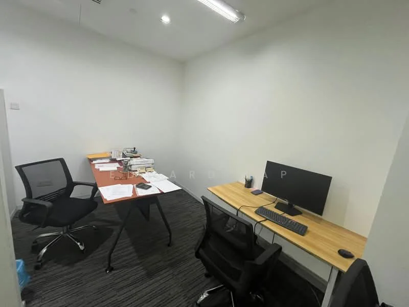 Study features: white painted walls, carpet flooring in dark grey, desk with wooden top, black office chair, grey office chair, computer monitor, keyboard, papers and documents on desk, table lamp, shelves with books and items; style: modern.