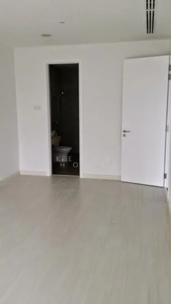 Room features: white painted walls, light-colored flooring, door with handle, visible bathroom door, no visible windows, minimalist design, ceiling with air vents, neutral color palette; style: modern.