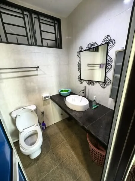 Bathroom features: white two-piece toilet, black countertop, round ceramic sink, framed mirror, wall-mounted towel rack, grey tiled walls, grey tiled flooring, window with black metal grille, waste basket; style: modern.