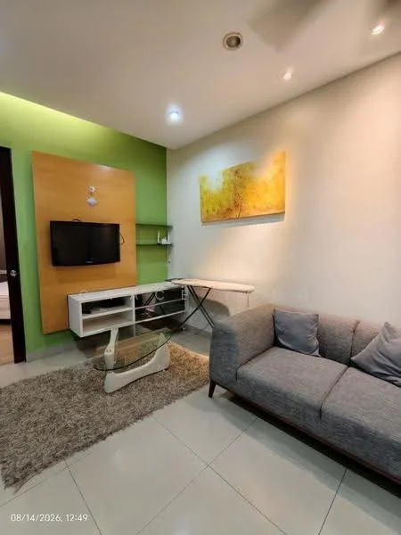 Living features: grey fabric sofa, white coffee table, TV console, wall-mounted TV, decorative artwork on wall, green accent wall, cream painted walls, recessed downlights, area rug with neutral color, glass shelving unit; style: modern.