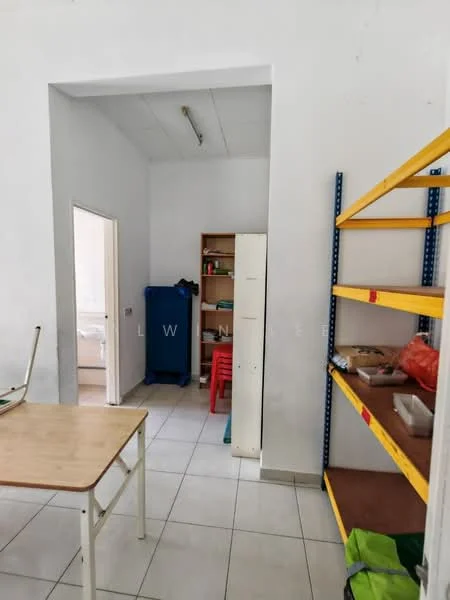 Room features: white painted walls, tile flooring, shelving unit with yellow frame, wooden table, red plastic chair, blue storage cabinet, open doorway leading to another room, visible storage boxes.