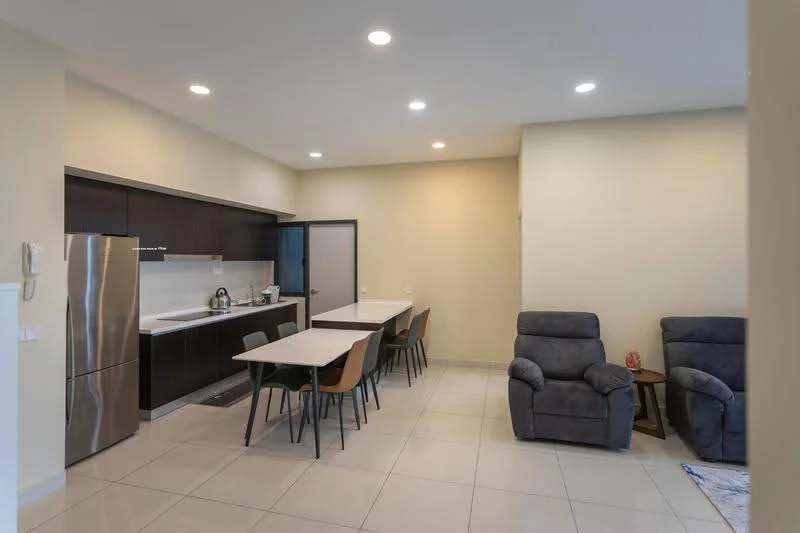Dining features: rectangular dining table with 6 chairs, grey upholstered dining chairs, light grey walls, recessed LED downlights, large stainless-steel fridge, built-in kitchen cabinetry in dark wood, white countertop, kettle, sink, dishwasher, tile flooring, two grey recliners, decorative item on side table; style: modern.
