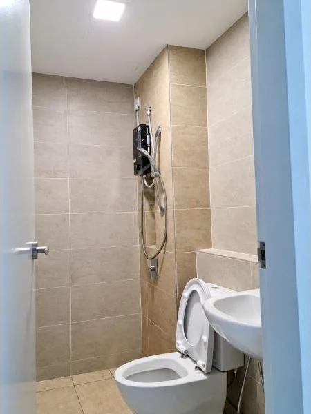 Bathroom features: beige tiled walls, beige ceramic tile flooring, recessed ceiling light, walk-in shower area, wall-mounted shower mixer, handheld shower, black shower heater unit, white one-piece toilet, white wall-mounted sink, partial-height tiled partition, light blue door frame, white painted ceiling; style: modern.