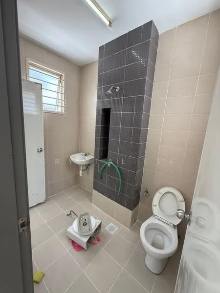 Bathroom features: grey tiled walls, beige tiled flooring, shower area with wall-mounted shower head, single-sink vanity with wall-mounted faucet, toilet, window with metal grille, door leading to hallway, plumbing visible for additional fixtures; style: modern.