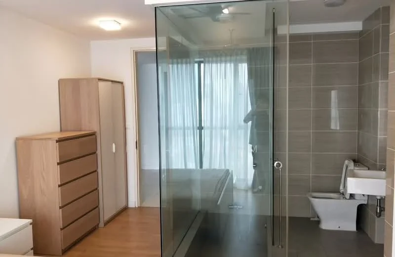 Room features: glass shower enclosure, tile flooring, wooden dresser with six drawers, white toilet, large window with sheer curtains, light fixture on ceiling, neutral wall color, built-in wardrobe, wooden flooring; style: modern; view: city.