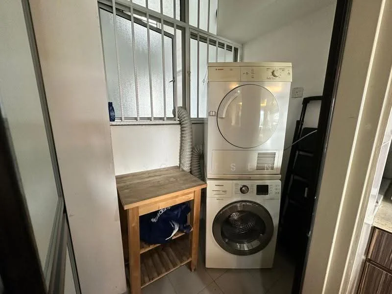 Laundry features: stacked washer and dryer, wooden laundry shelf, white walls, tile flooring, window with metal grille, laundry basket, vent hose, corner space.
