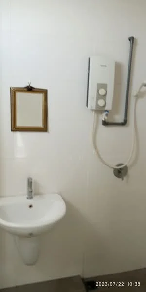 Bathroom features: white ceramic sink, chrome faucet, wall-mounted mirror in gold frame, white tiled walls, shower head with adjustable height, water heater unit, grey tile flooring; style: modern.