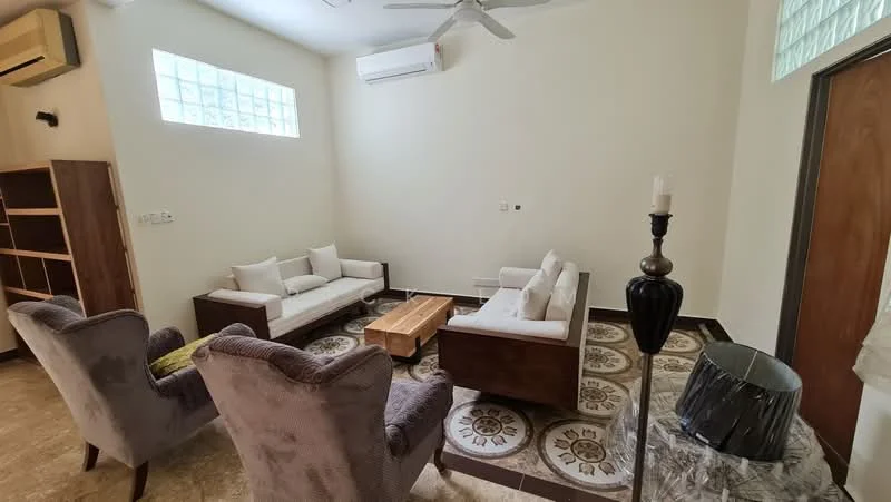 Living features: 2-seater fabric sofa in white, 3-seater fabric sofa in white, wooden coffee table, 2 upholstered armchairs in grey, ceiling fan, wall-mounted split AC, decorative candle holder, tile flooring with decorative pattern, light-colored painted walls, glass block windows; style: modern.