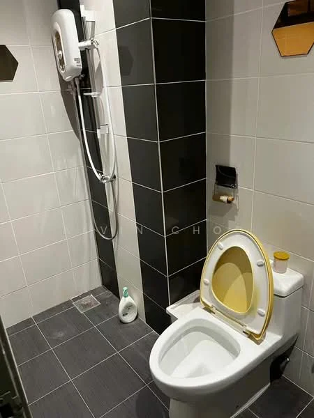 Bathroom features: white two-piece toilet, yellow toilet seat, shower with handheld showerhead, wall-mounted shower mixer, grey floor tiles, black and white wall tiles, soap dispenser, drain in floor; style: modern.