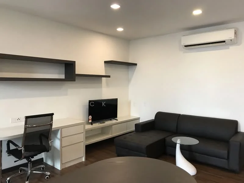 Living features: black L-shape sectional sofa, white coffee table, TV console with flat-screen TV, wall-mounted shelves, desk with ergonomic chair, wall-mounted split AC, wooden flooring, recessed downlights, white painted walls; style: modern.