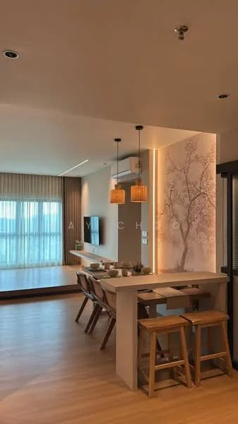 Dining features: wooden dining table, 4 wooden stools, pendant lighting, wall-mounted TV, floor-to-ceiling windows, light wood flooring, decorative wall with tree design, air conditioning unit; style: modern; view: city. Living features: light wood flooring, floor-to-ceiling windows, sofa area, decorative wall with tree design, recessed lighting; style: modern; view: city.