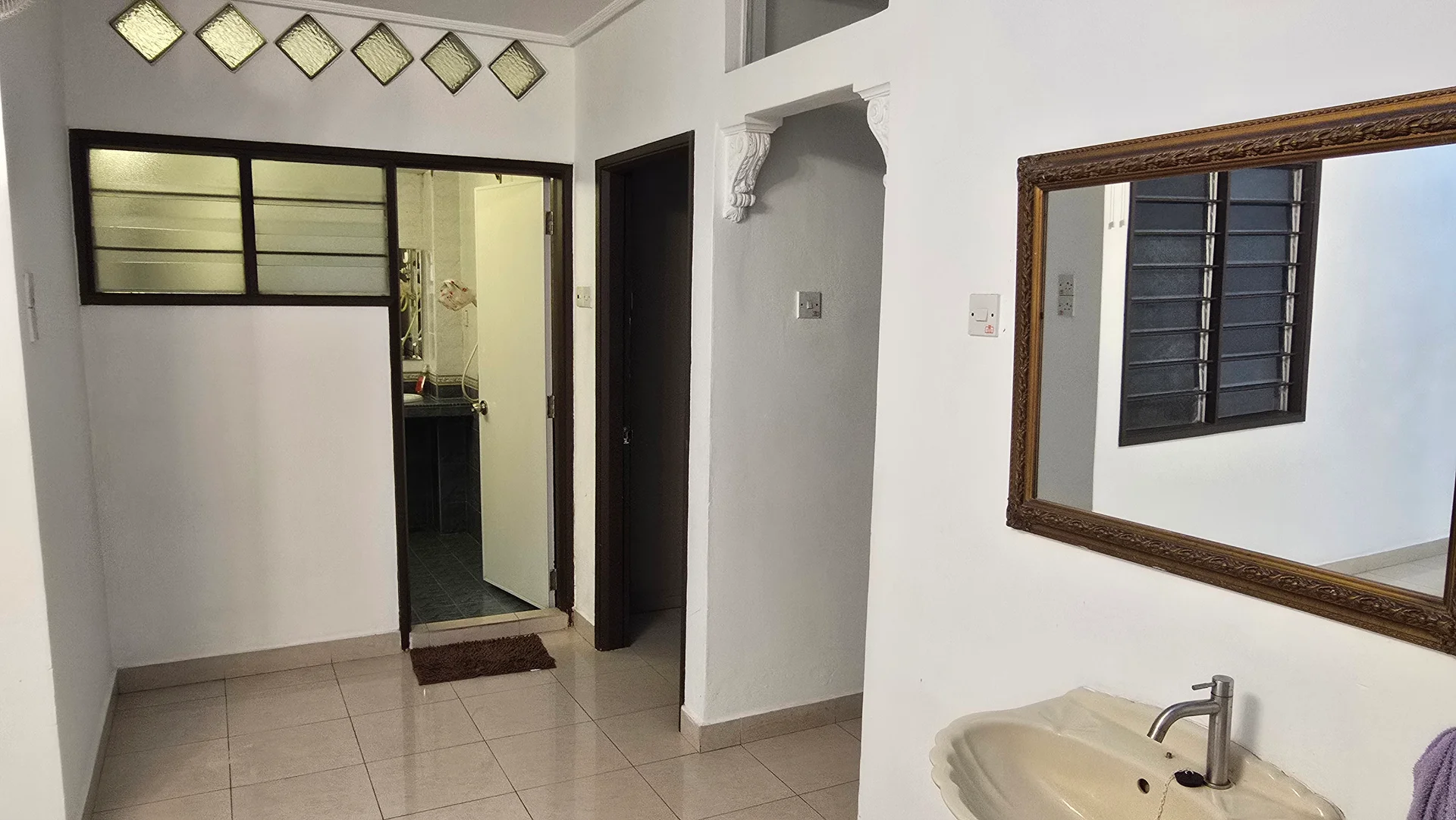 Room features: white painted walls, tile flooring, mirror above sink, sink with faucet, doorway leading to another room, window with grille, decorative wall feature, doormat; style: modern.