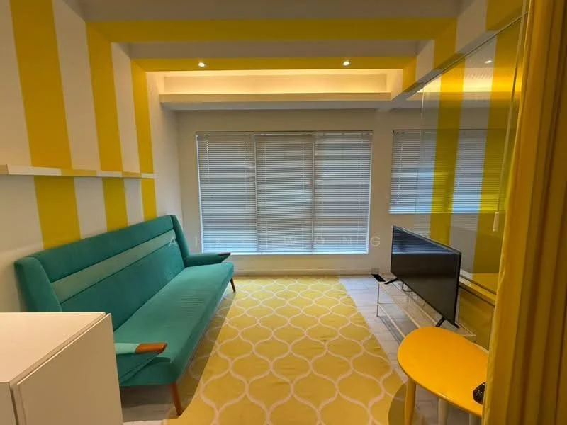 Living features: green fabric sofa, yellow accent wall with stripes, white walls, recessed ceiling lights, blinds on windows, TV console, flat-screen TV, round yellow coffee table, area rug with geometric pattern, white shelving unit; style: modern.