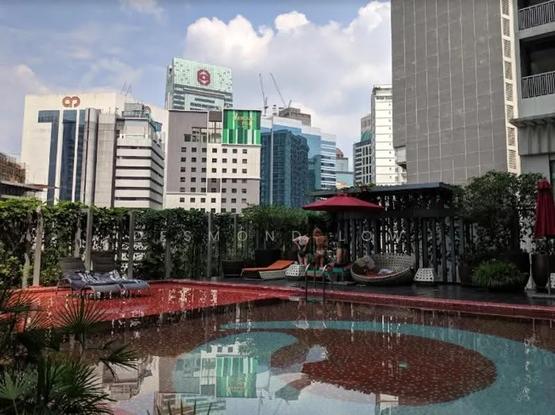 Exterior type: swimming pool deck; features: infinity pool, pool deck with loungers, red patterned flooring, surrounded by greenery, city skyline view, umbrella shades, hammock area, high-rise buildings in background; style: modern.