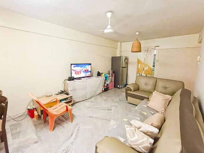 Living features: light grey marble flooring, white painted walls, 5-blade ceiling fan, sofa in beige, coffee table, wall-mounted TV, refrigerator, decorative pendant light, area rug with geometric pattern, plastic chair in orange, open shelving unit, decorative throw pillows; style: modern.