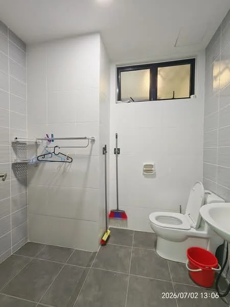 Bathroom features: white tiled walls, grey tiled flooring, toilet, sink with faucet, shower area with glass partition, window for natural light, towel rack, cleaning supplies, broom, bucket; style: modern.
