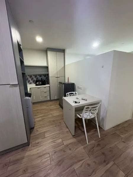 Kitchen features: light wood cabinetry, grey countertop, black and white tiled backsplash, stainless-steel fridge, built-in oven, single-bowl stainless-steel sink, chrome pull-down faucet, wood-look laminate flooring, dining table, white plastic chairs, recessed ceiling lights; style: modern.