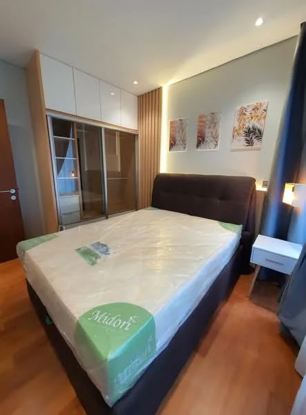 Bedroom features: king-size bed with upholstered headboard, mattress wrapped in plastic, wooden flooring, built-in wardrobe with sliding doors, white bedside table, wall-mounted light fixtures, decorative wall art, curtains, recessed ceiling lights; style: modern.