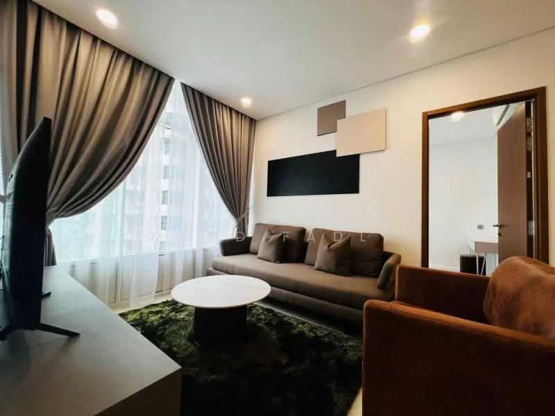 Living features: 3-seater fabric sofa in grey, 2-seater fabric sofa in brown, round coffee table with black base, floor-to-ceiling windows with sheer curtains, green area rug, wall-mounted TV, decorative wall art panels, recessed ceiling lights; style: modern.